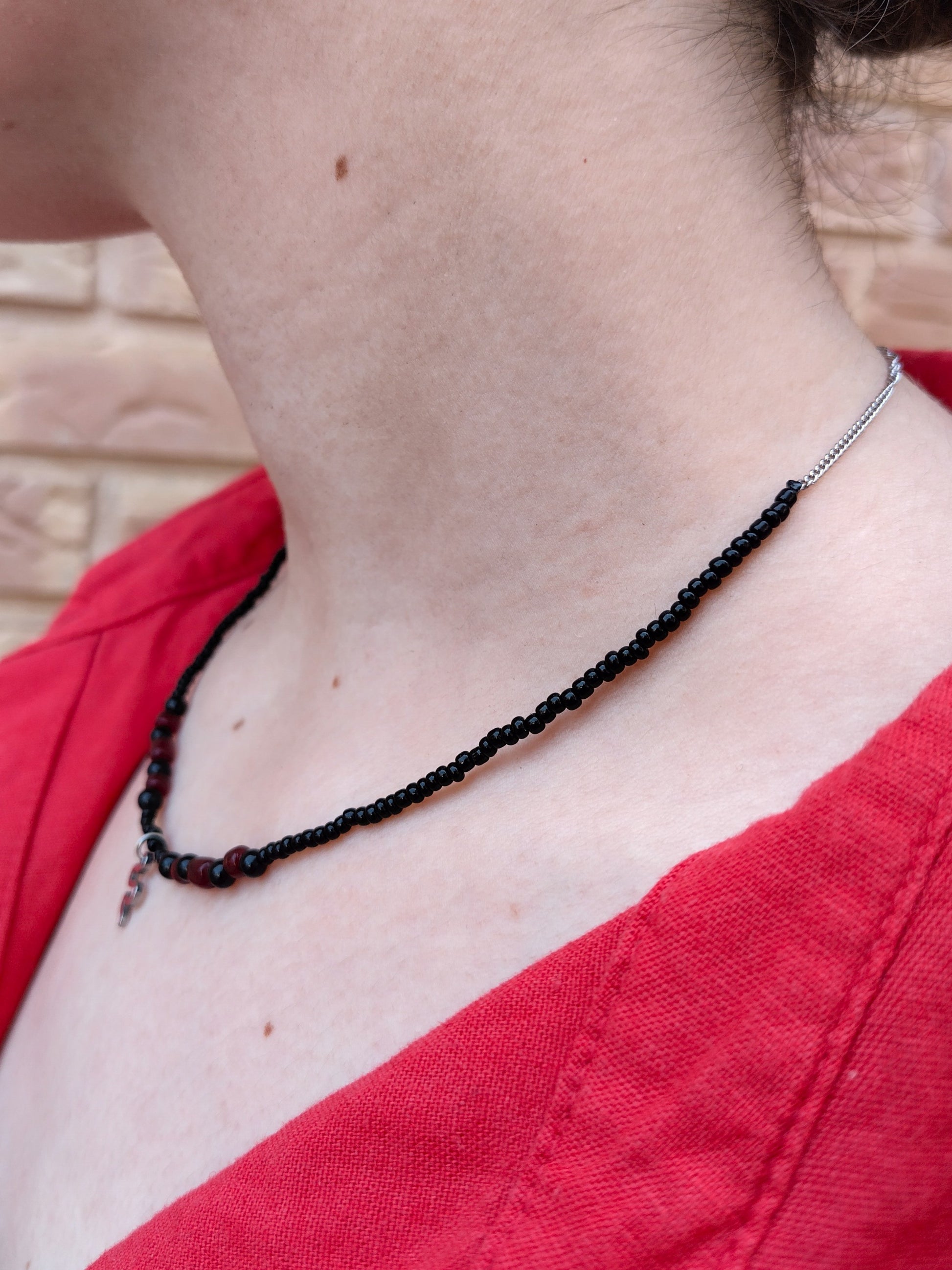 Collar de cuentas de vidrio y piedra en negro y granate, con cadena y colgante de serpiente plateados.