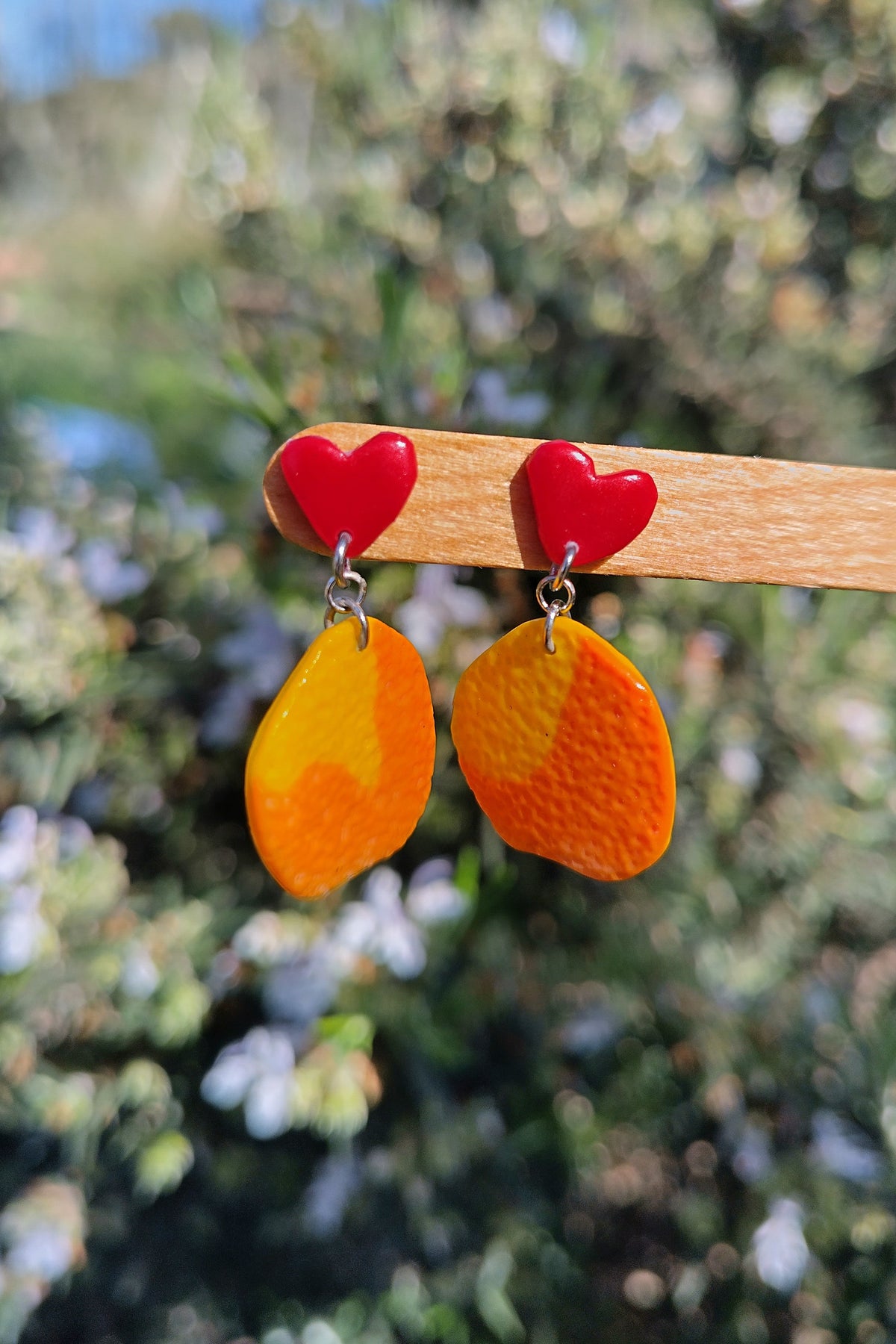 Pendientes de naranjas colgando de corazones rojos pequeños. Primaverales y con agradable textura.
