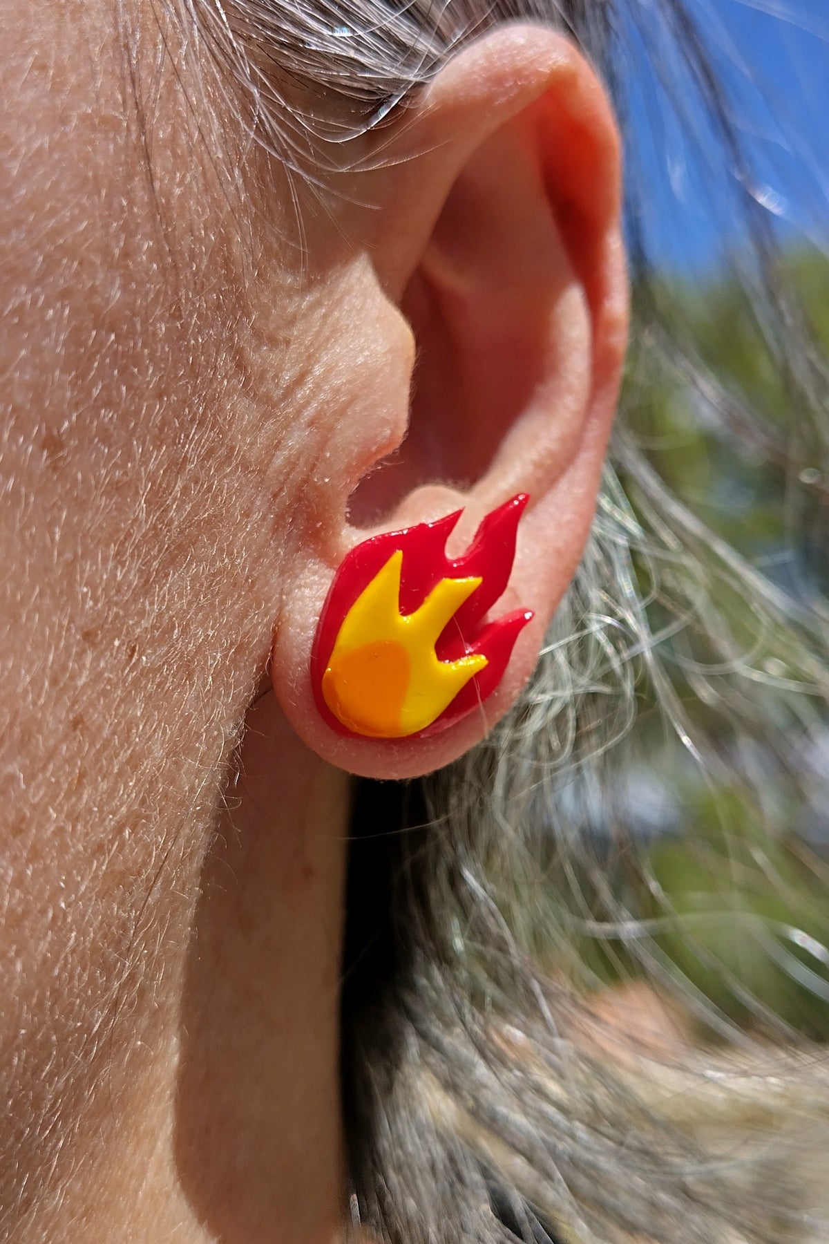 Pendientes de acero inoxidable en forma de llama roja y amarilla, que quedan pegados al lóbulo una vez puestos.